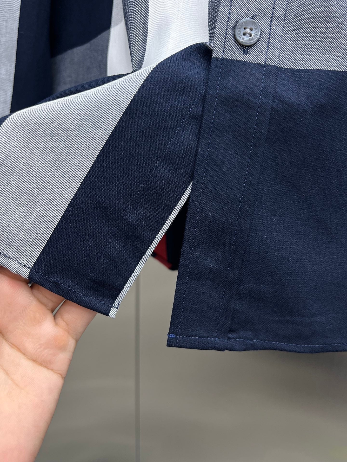Navy long-sleeve shirt cuff with button and contrast striped fabric