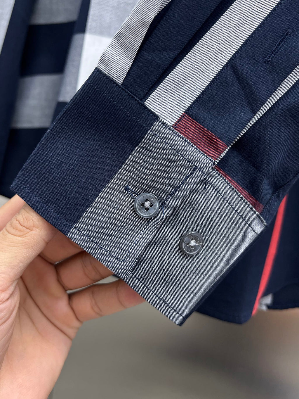 Navy shirt sleeve cuff with two buttons and red-gray check lining