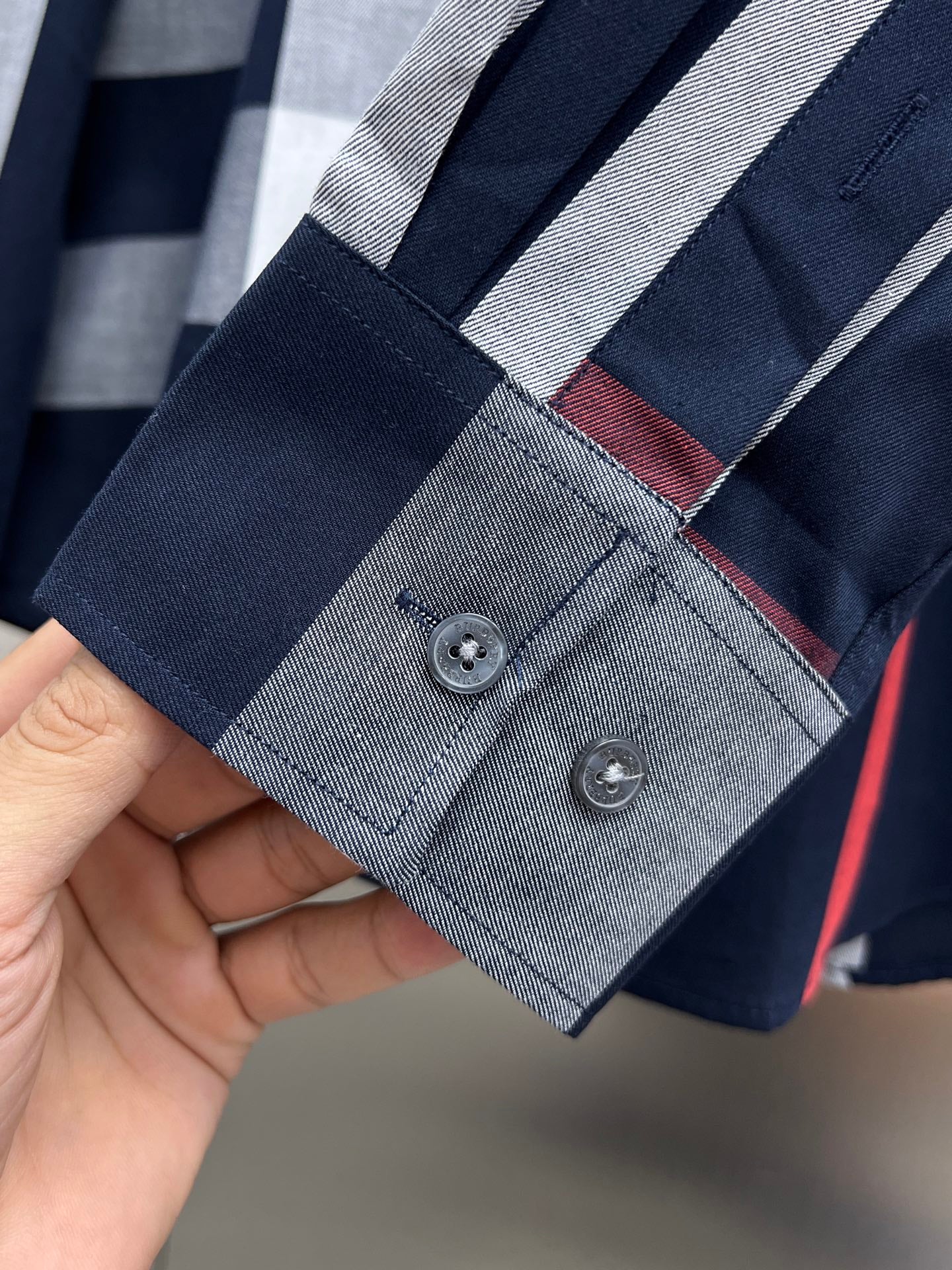 Navy shirt sleeve cuff with two buttons and red-gray check lining