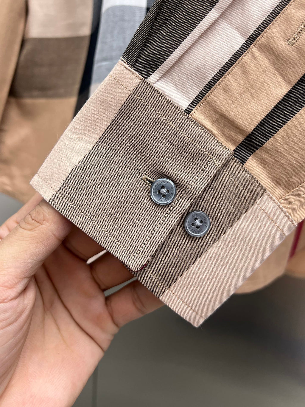 Beige plaid shirt sleeve cuff with two buttons and stitched placket