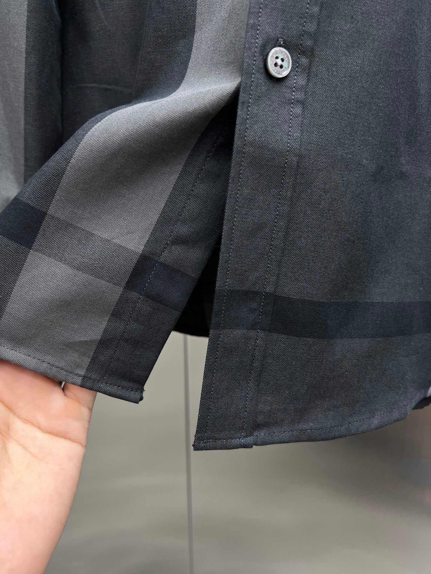 Dark long-sleeve shirt cuff with round buttons and check trim