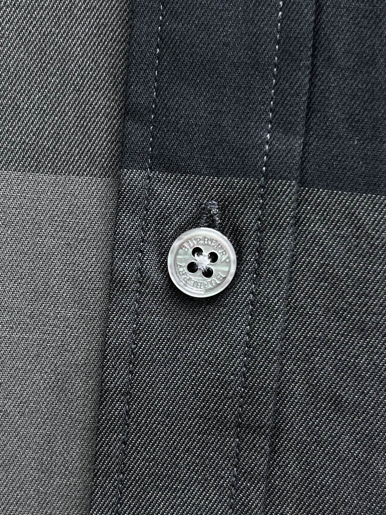 Burberry check shirt button and stitched placket detail on dark blue-gray fabric