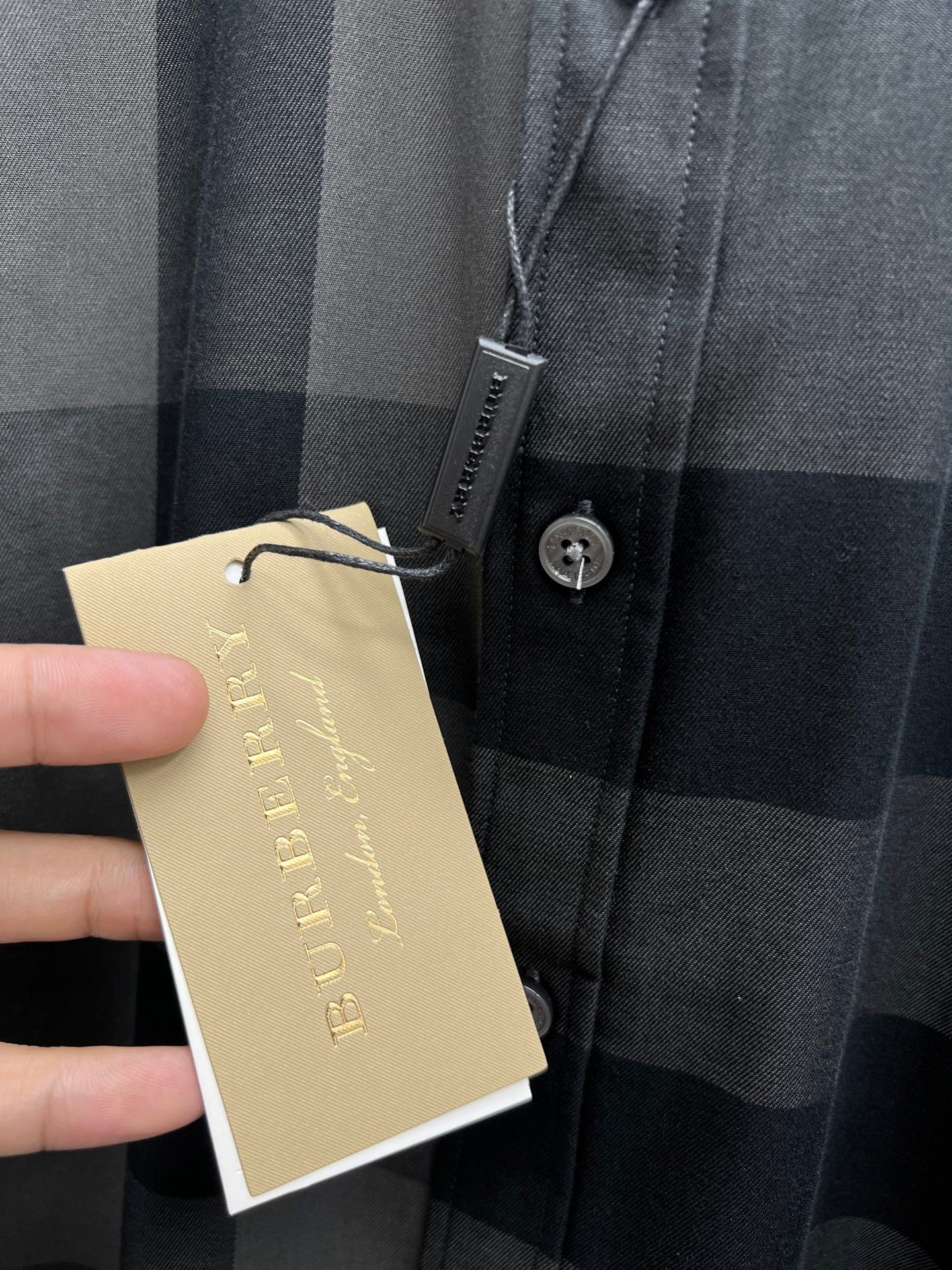 Burberry check shirt with button placket and hangtag at chest, dark blue-gray plaid