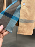 Check-pattern long shirt cuff on tan fabric with blue and dark stripes and button tab