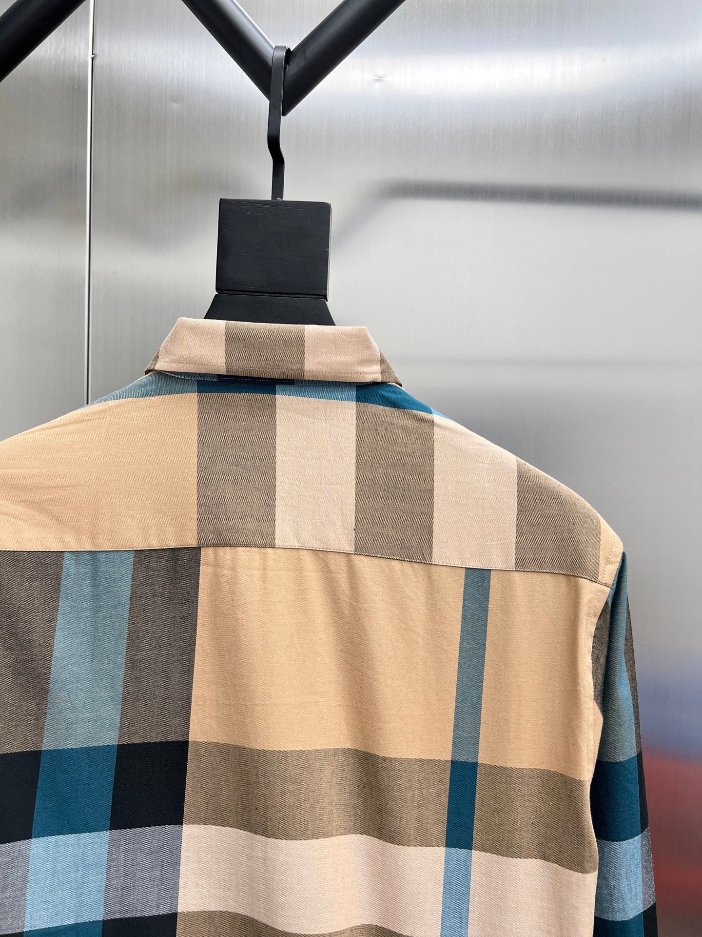 Check-pattern long shirt on hanger with tan, blue, and dark block squares