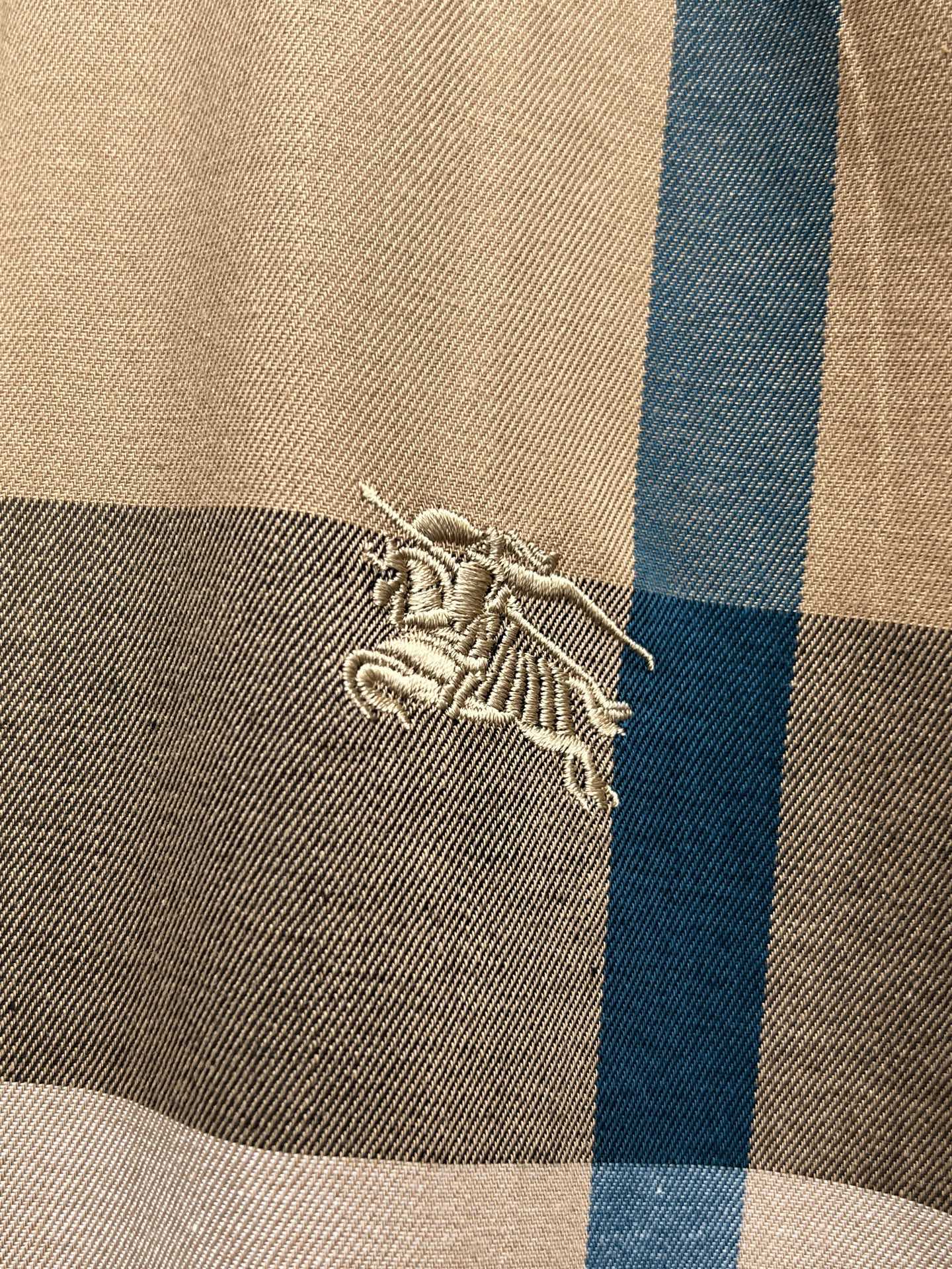 Burberry embroidered crest logo on beige and blue plaid fabric