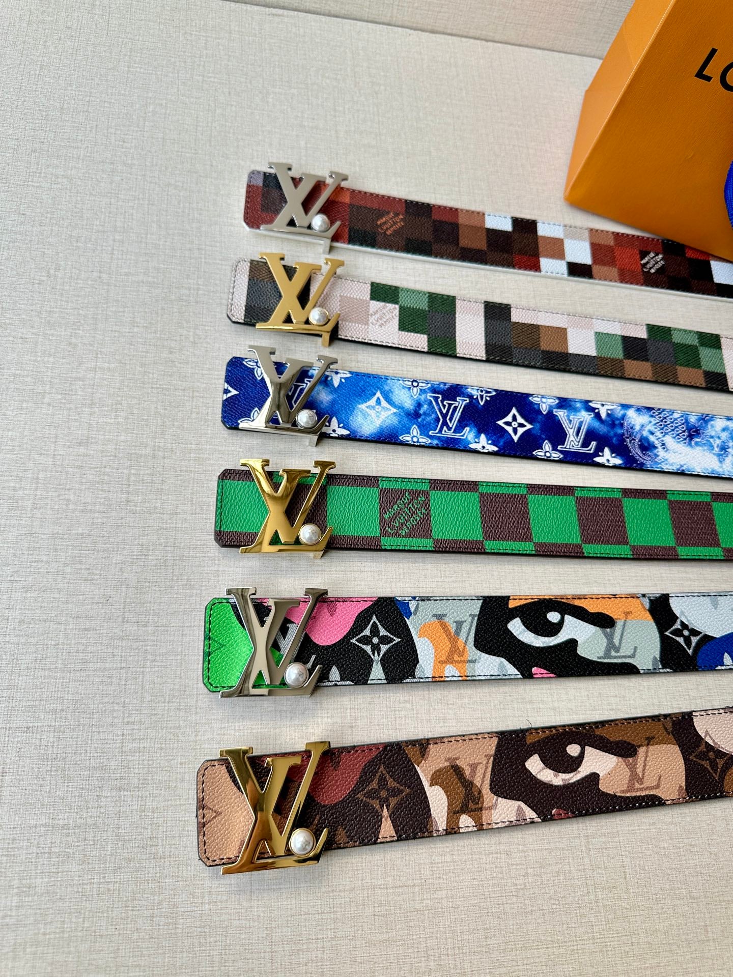 Assorted LV belt designs with gold-toned buckle hardware and patterned straps