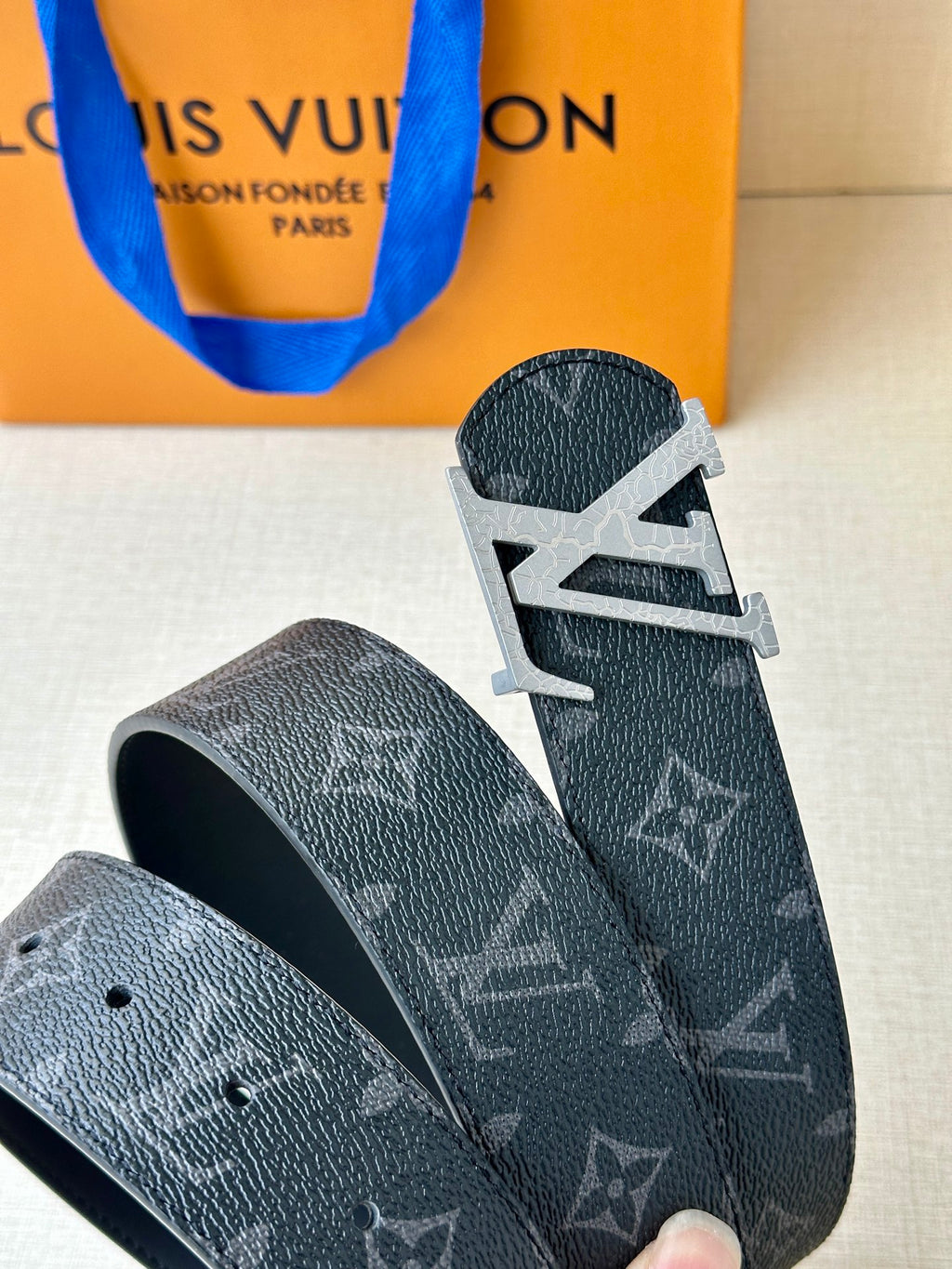 Louis Vuitton monogram belt with textured dark strap and silver-tone buckle close-up