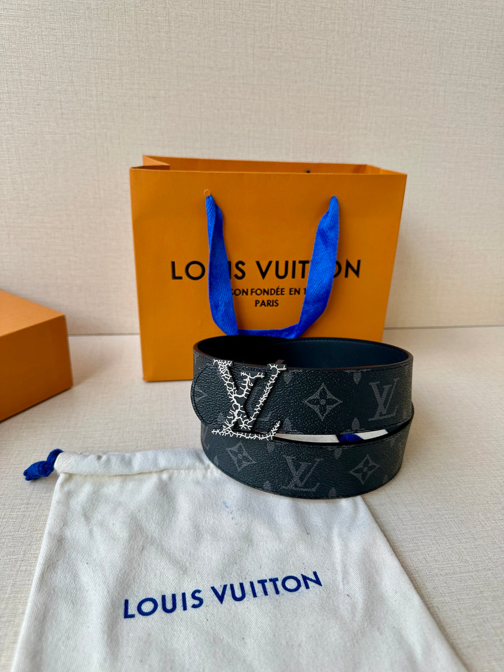 Louis Vuitton monogram belt, dark strap and silver-tone LV buckle on dust bag