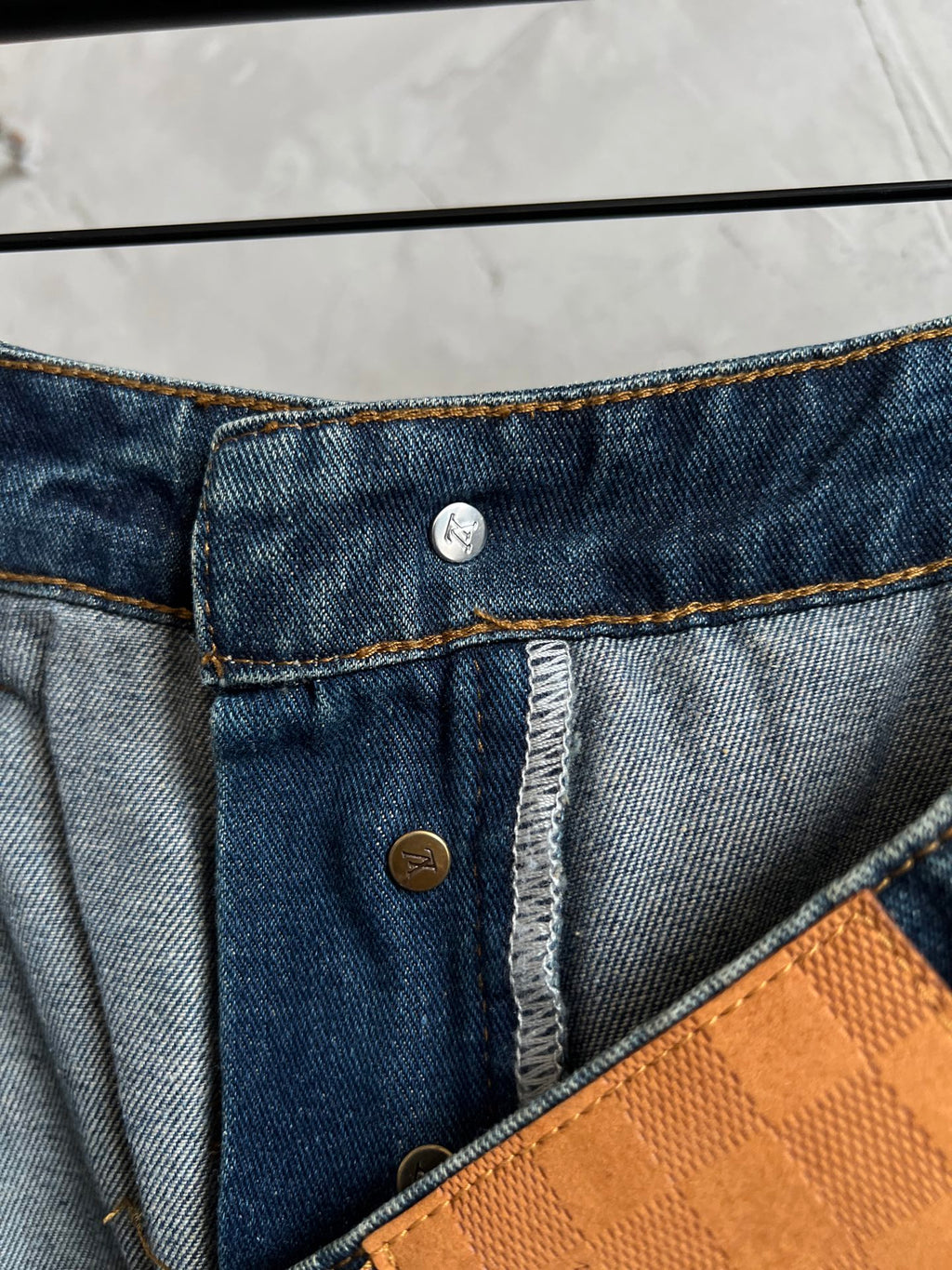 Dark blue denim waistband with coin pocket button and tan/gold contrast stitching