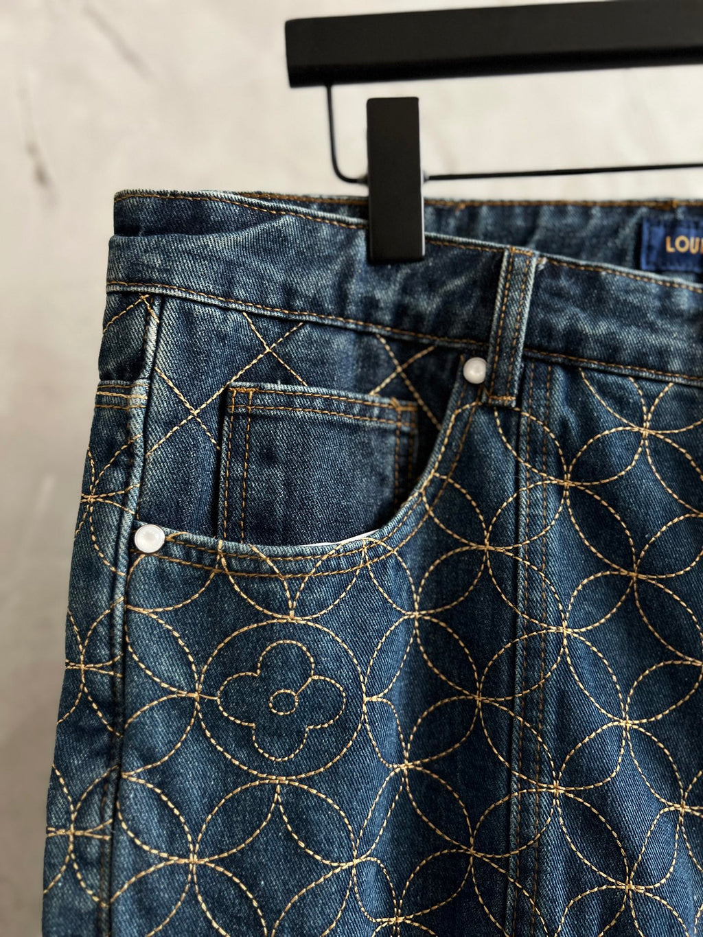 Dark blue denim pants front pockets with gold vine embroidery and button