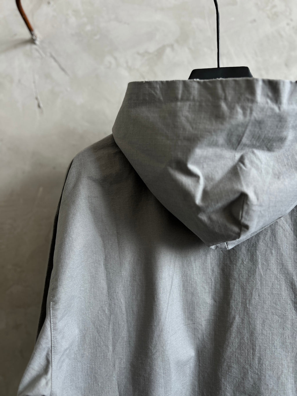 Light gray hooded jacket with raised hood and front zipper