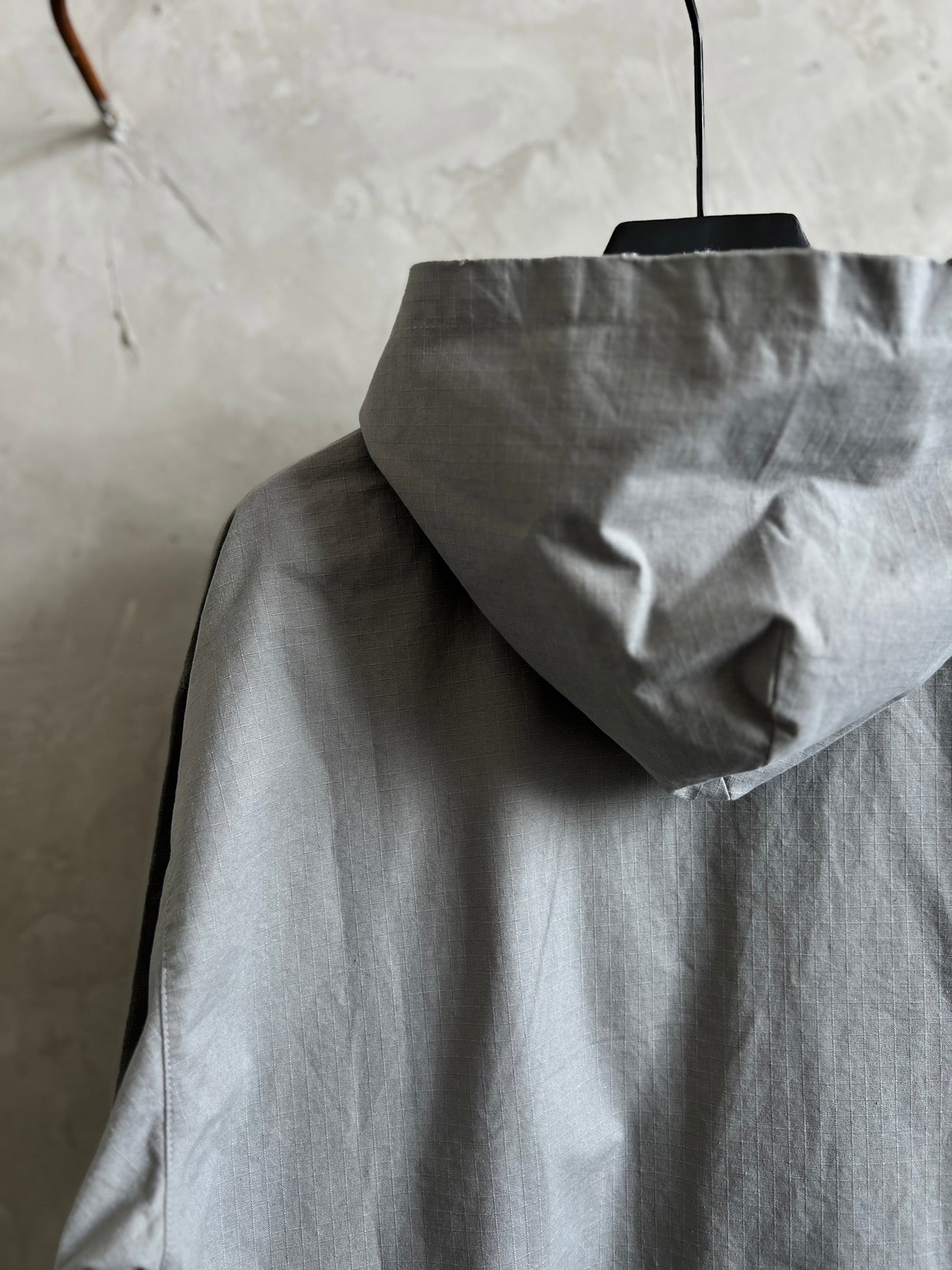 Light gray hooded jacket with raised hood and front zipper