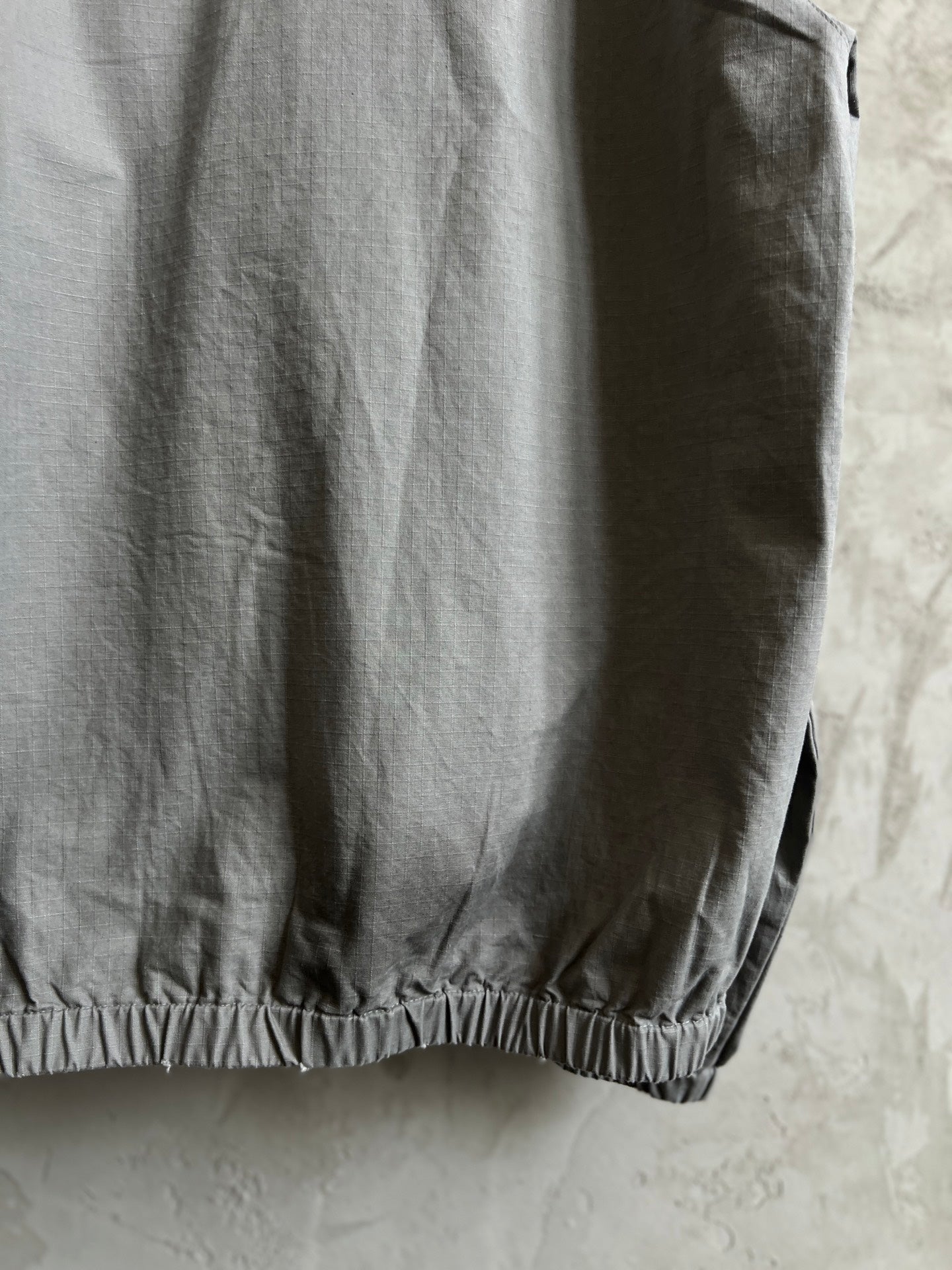 Light gray hooded jacket side view with elastic hem detail