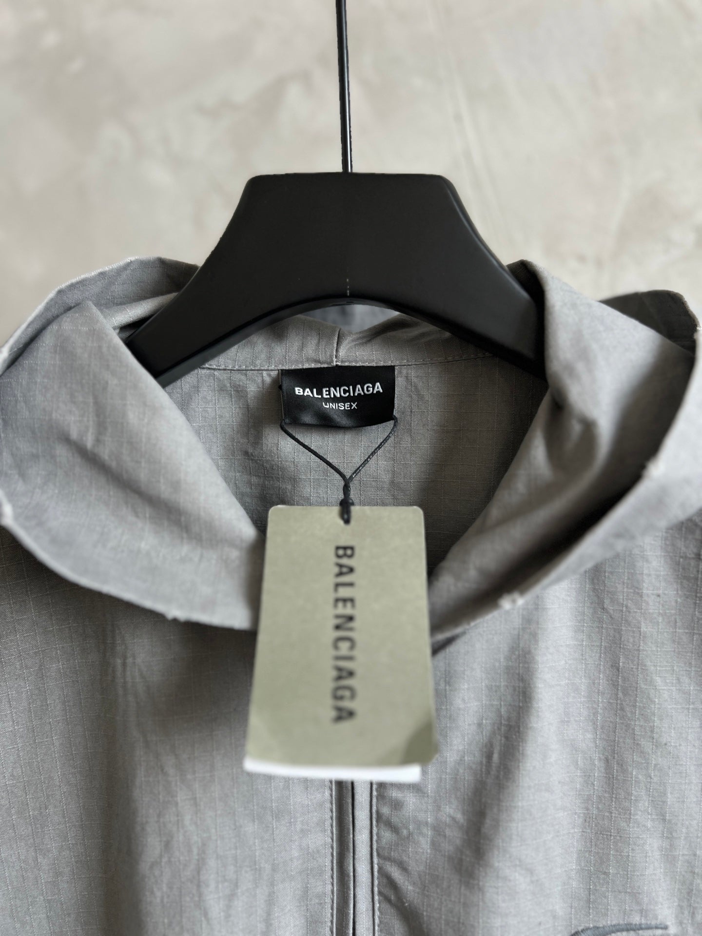 Light gray hooded jacket with neck label on hanger and hood opening