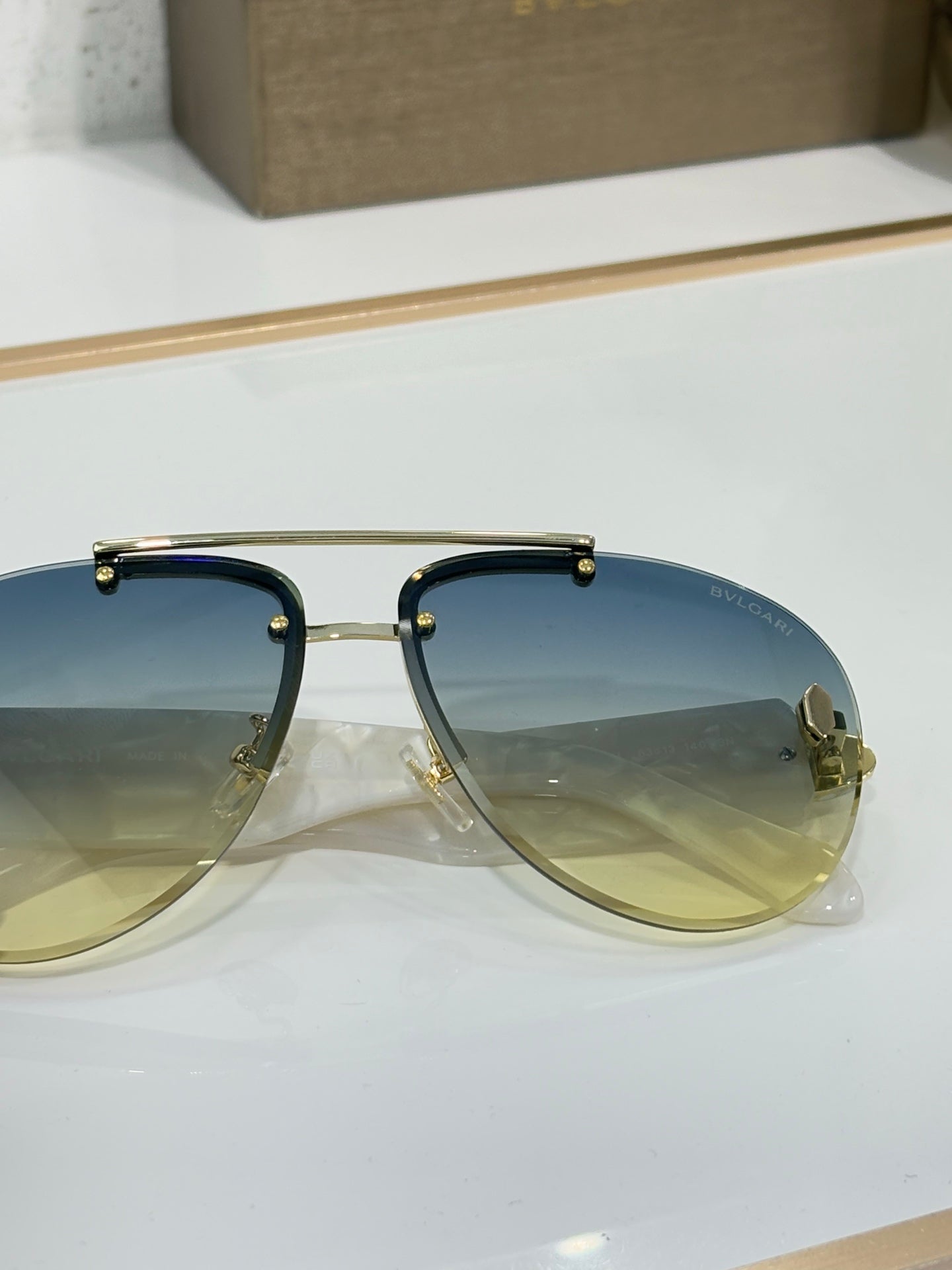 Close-up of metal sunglasses with blue gradient lenses and gold-tone frame