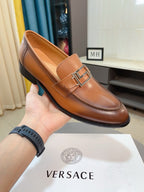 Versace leather penny loafer with square buckle, tan-brown, held in hand