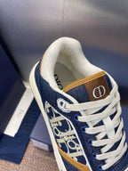 Dior unisex sneakers close-up, navy and white with tan strap and printed logo