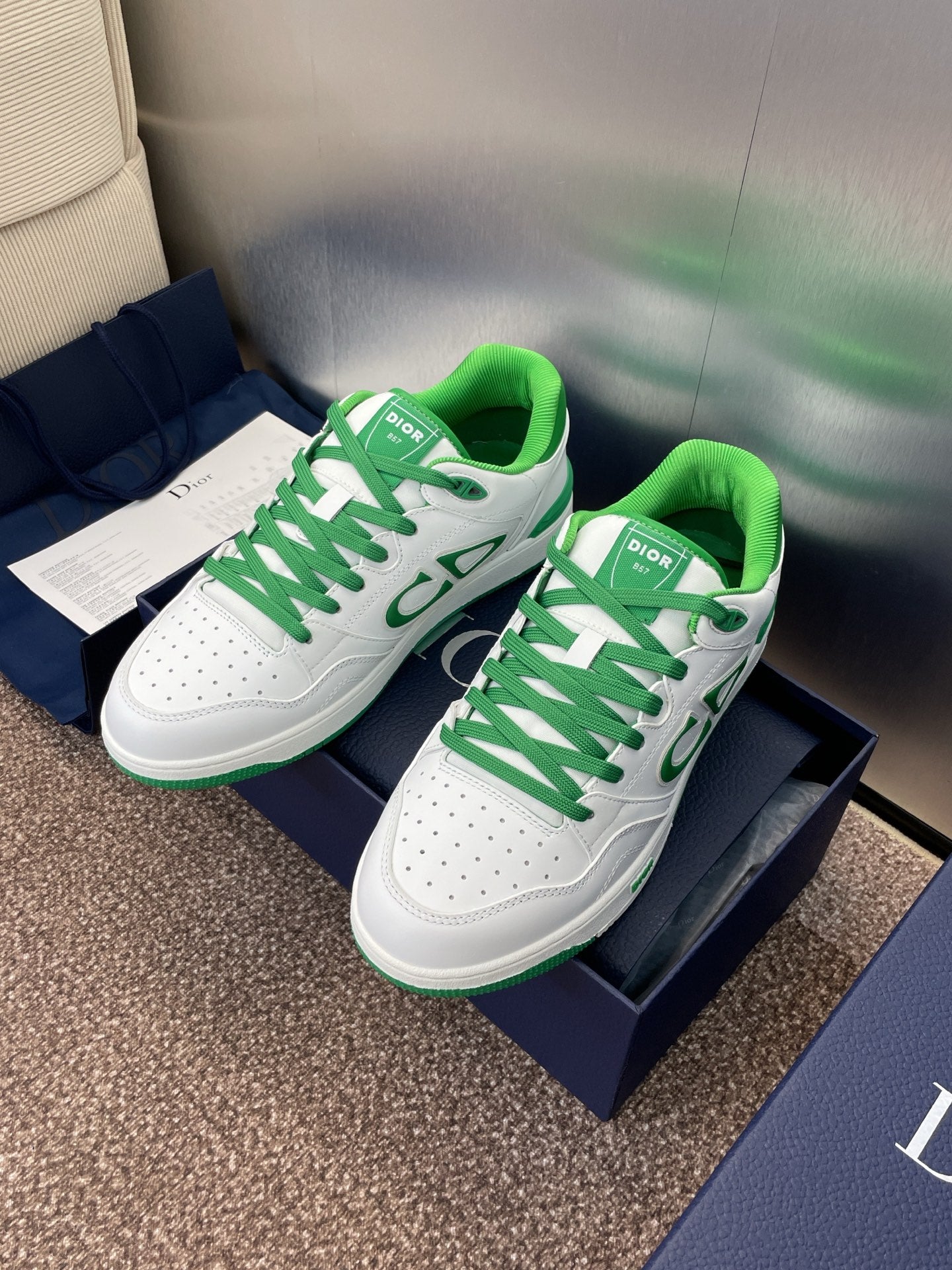 Pair of white low-top sneakers with green laces and CD-style side logo