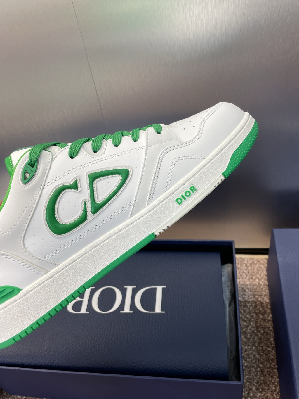 Side view of white low-top sneakers with green CD-style logo and branding strip