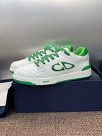 White low-top sneakers with green laces and side CD-style logo detail