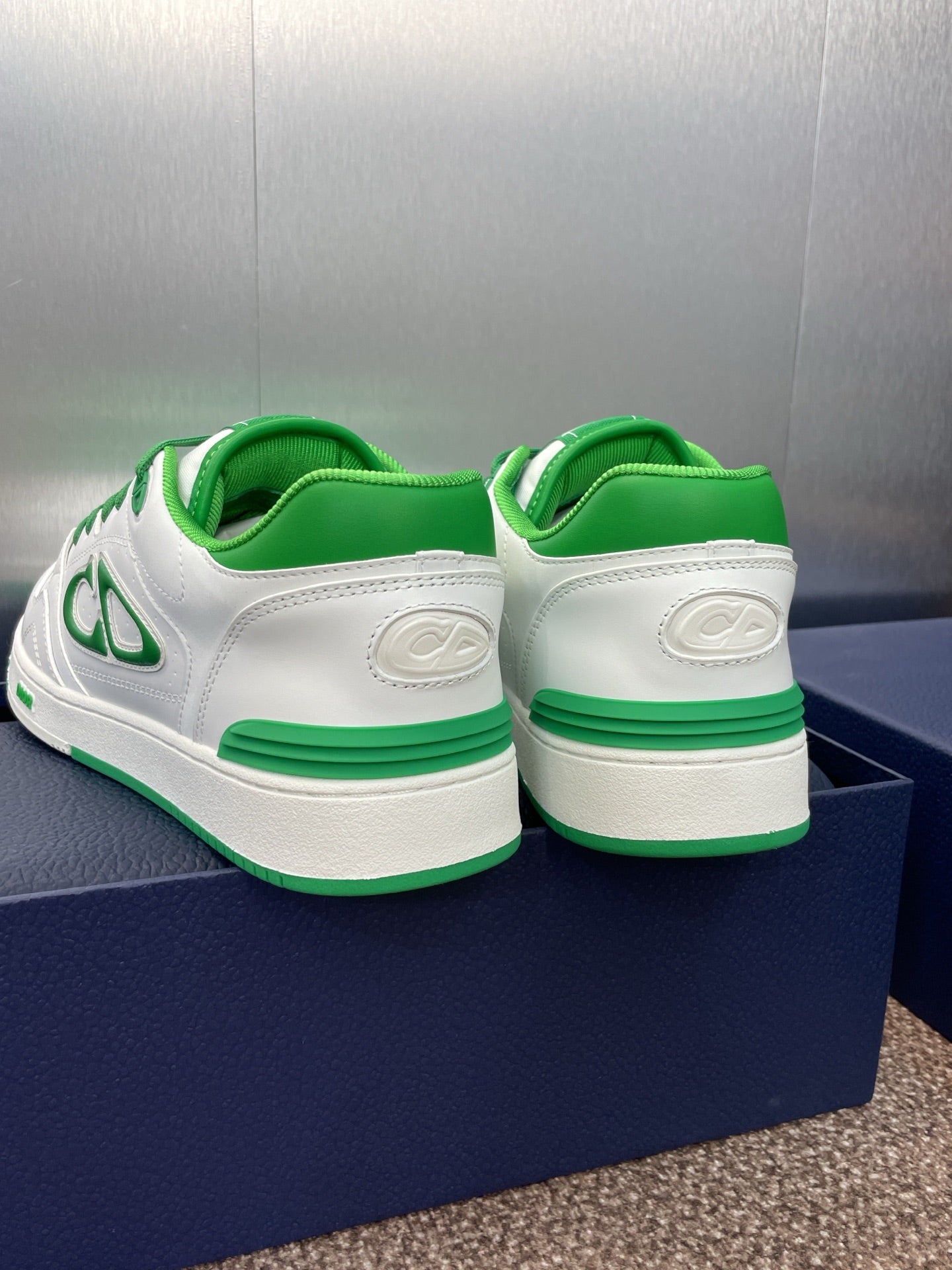 Back view of white low-top sneakers with green heel tabs and green-trim sole