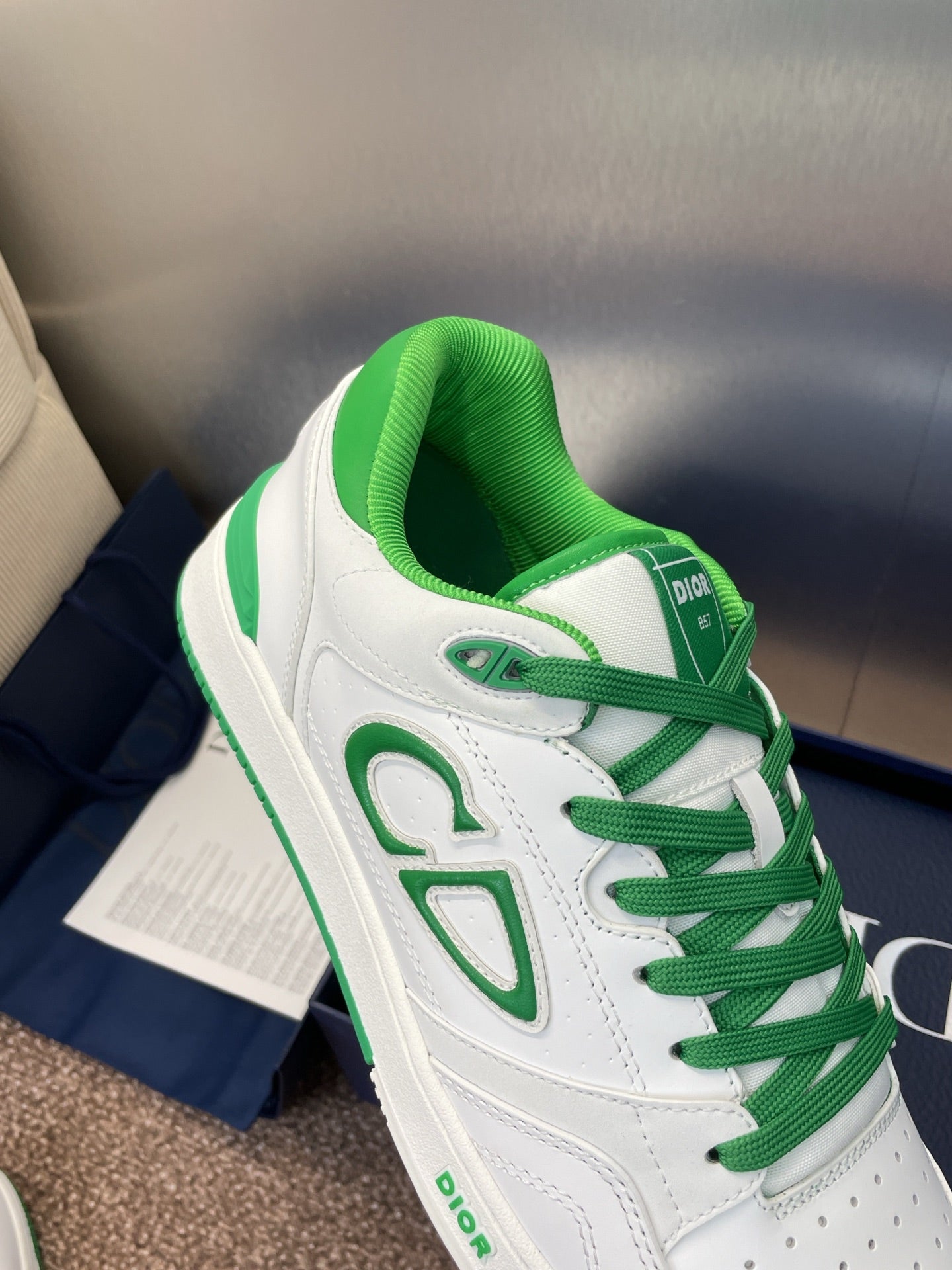 Front/side view of white low-top sneakers with green laces and CD-style logo