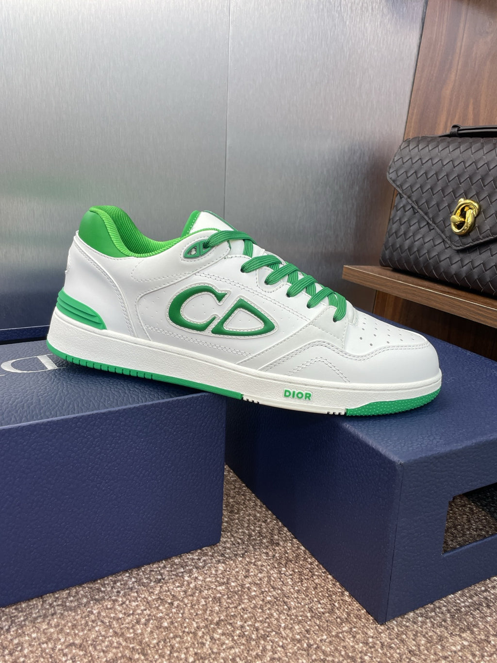 White low-top sneakers with green laces and CD-style side logo on shoe box