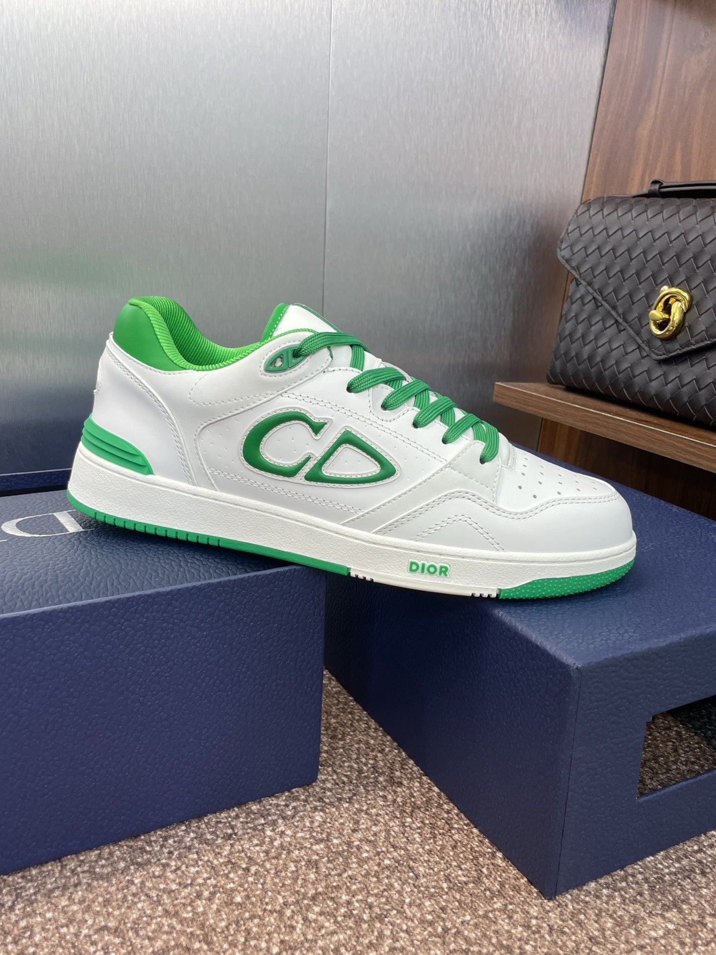 White low-top sneakers with green laces and CD-style side logo on shoe box