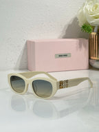 MiuMiu sunglasses with light cream frames and pale tinted lenses, gold logo on temples
