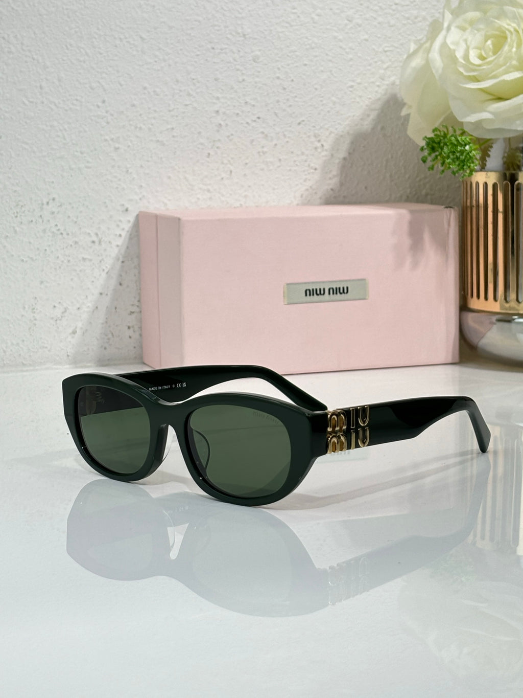 MiuMiu sunglasses with dark green frames and green tinted lenses, gold logo detail