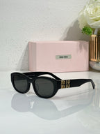 MiuMiu cat-eye sunglasses with black frames and dark lenses, gold logo on temples