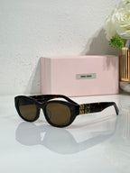 MiuMiu sunglasses with black frames and dark tinted lenses, gold logo on temples