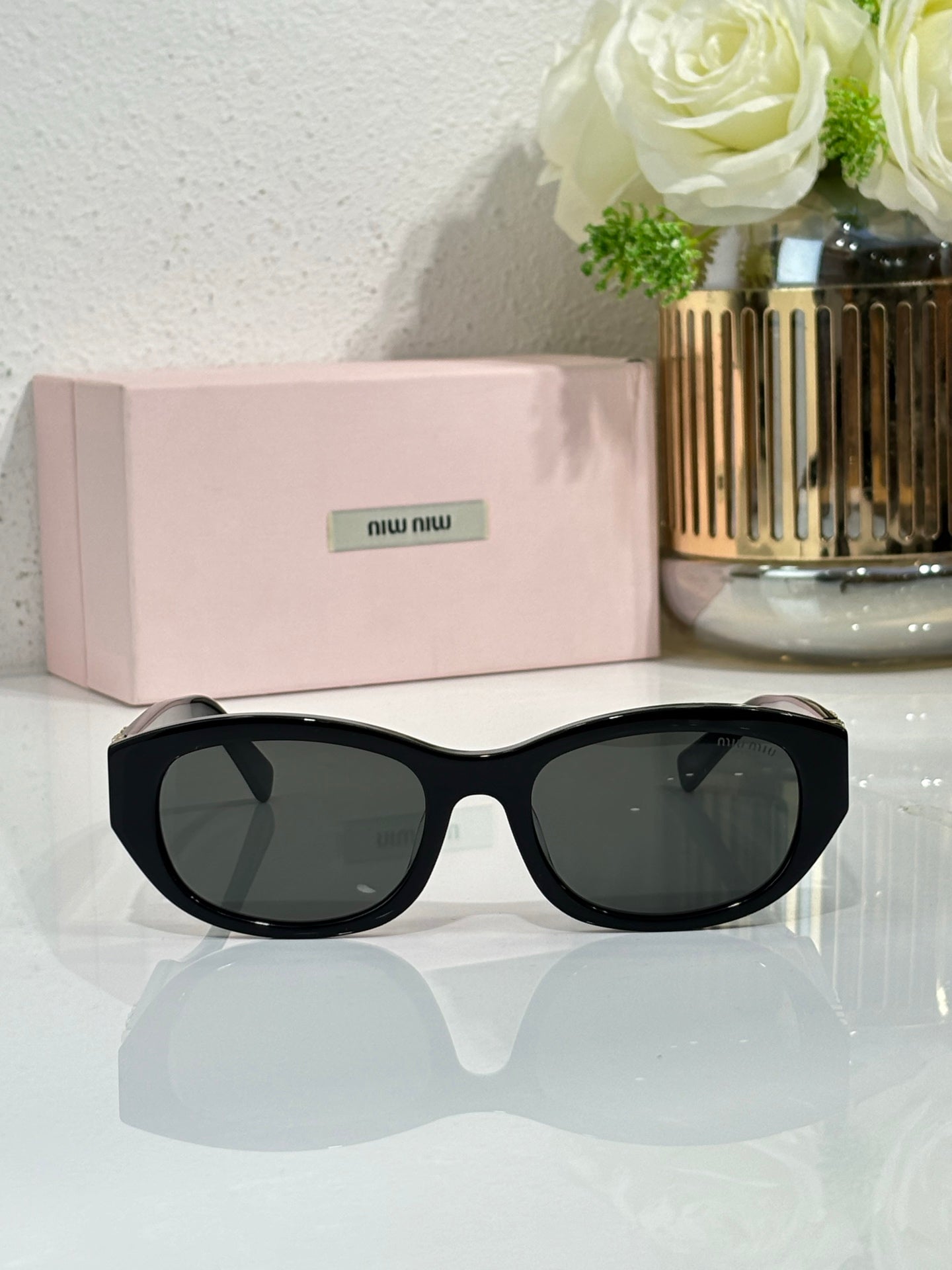 MiuMiu cat-eye sunglasses, front view, black frames and tinted dark lenses