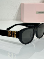 MiuMiu cat-eye sunglasses, angled view, black frames with gold Miu Miu emblem