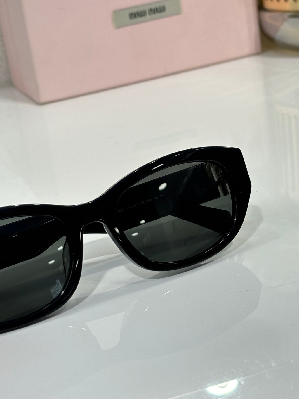 MiuMiu sunglasses lens close-up, glossy black frame with dark tinted lens