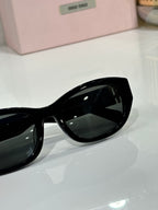 MiuMiu sunglasses lens close-up, glossy black frame with dark tinted lens
