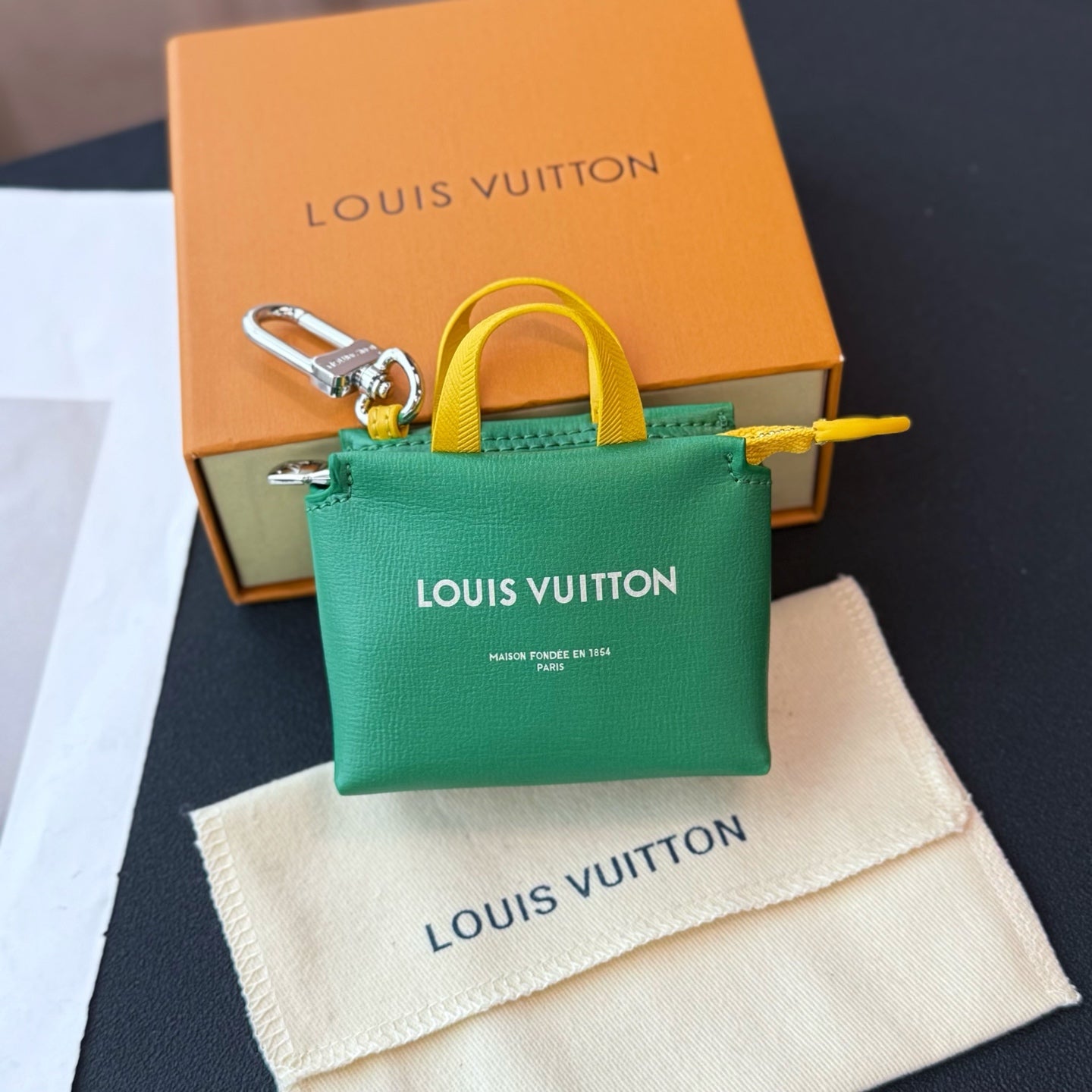 Louis Vuitton small bag with green body, yellow handle, and silver clasp; logo on front