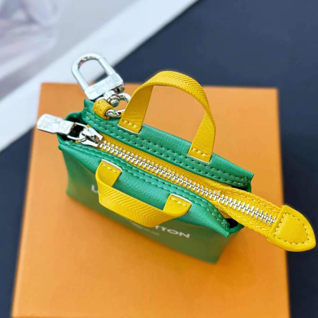 Louis Vuitton small bag with green zipper pouch, yellow wrist strap, and silver zipper pull