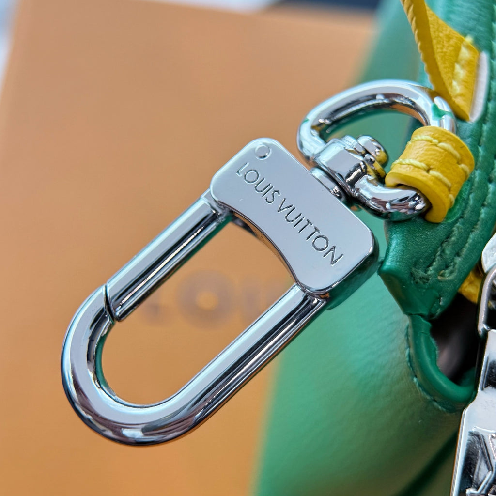 Louis Vuitton bag close-up of silver clasp hardware with green strap and yellow edging