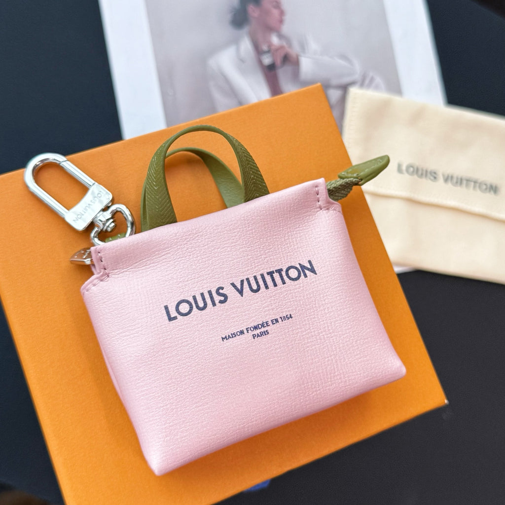 Pink small leather bag with green handle, silver zip, and Louis Vuitton logo on front.