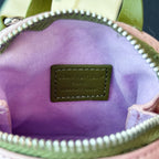 Small bag interior with purple lining and Louis Vuitton brand patch on green leather.