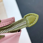 Pink small bag with green zipper track and green leather tab at the edge.