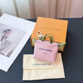 Pink small leather bag with green top handle, silver zip closure, Louis Vuitton logo.