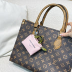 Brown monogram handbag with top handles and pink mini pouch charm
