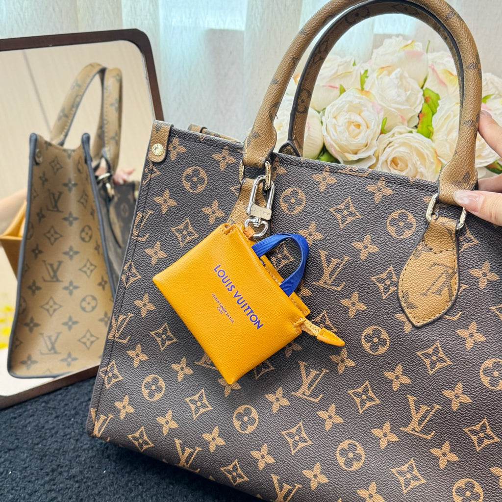 Brown monogram handbag with top handles and yellow mini pouch charm