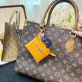 Brown monogram handbag with top handles and yellow mini pouch charm