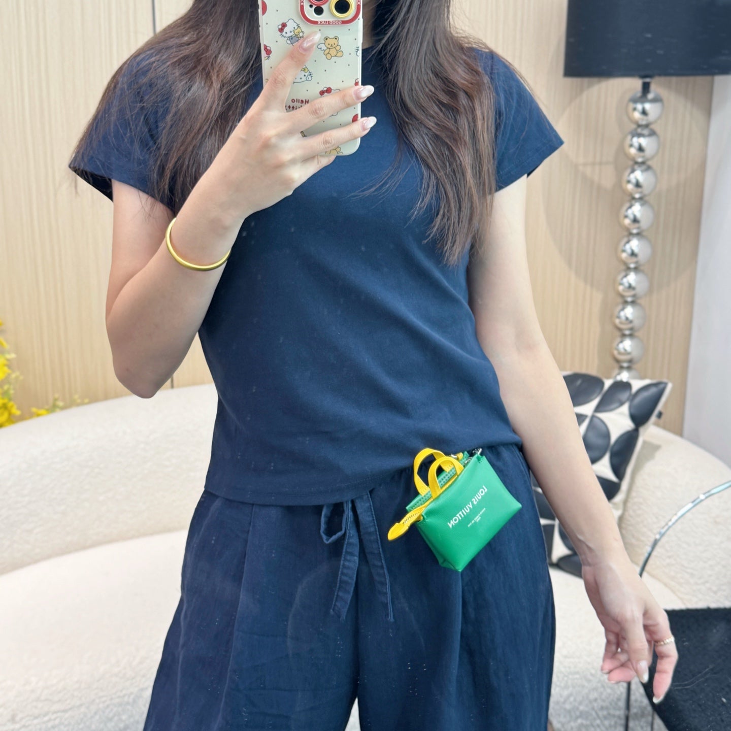 Green mini pouch bag with yellow cord, clipped to waistband