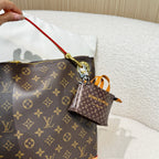 Brown monogram handbag with red zipper pull and small brown pouch charm
