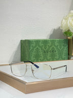 Eyeglasses with gold metal rectangular frame, clear lenses, and dark blue temple detail